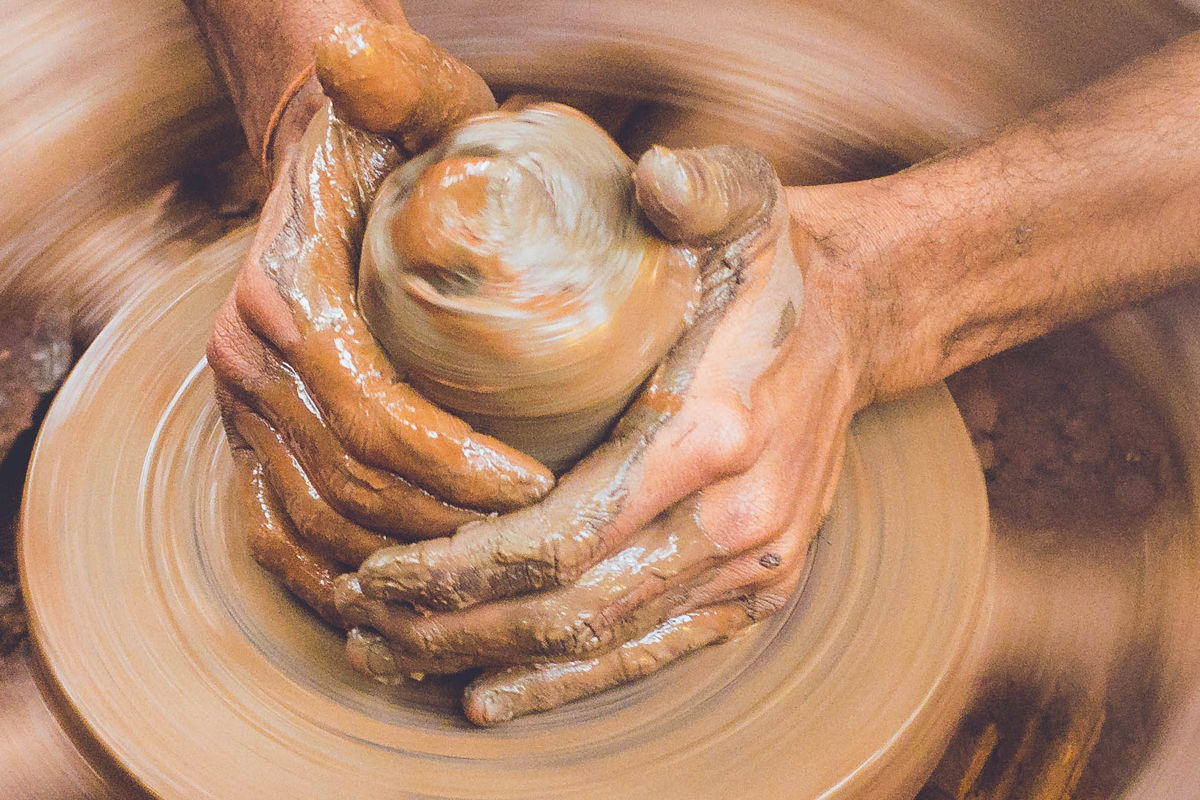 Hands working clay at a pottery wheel.