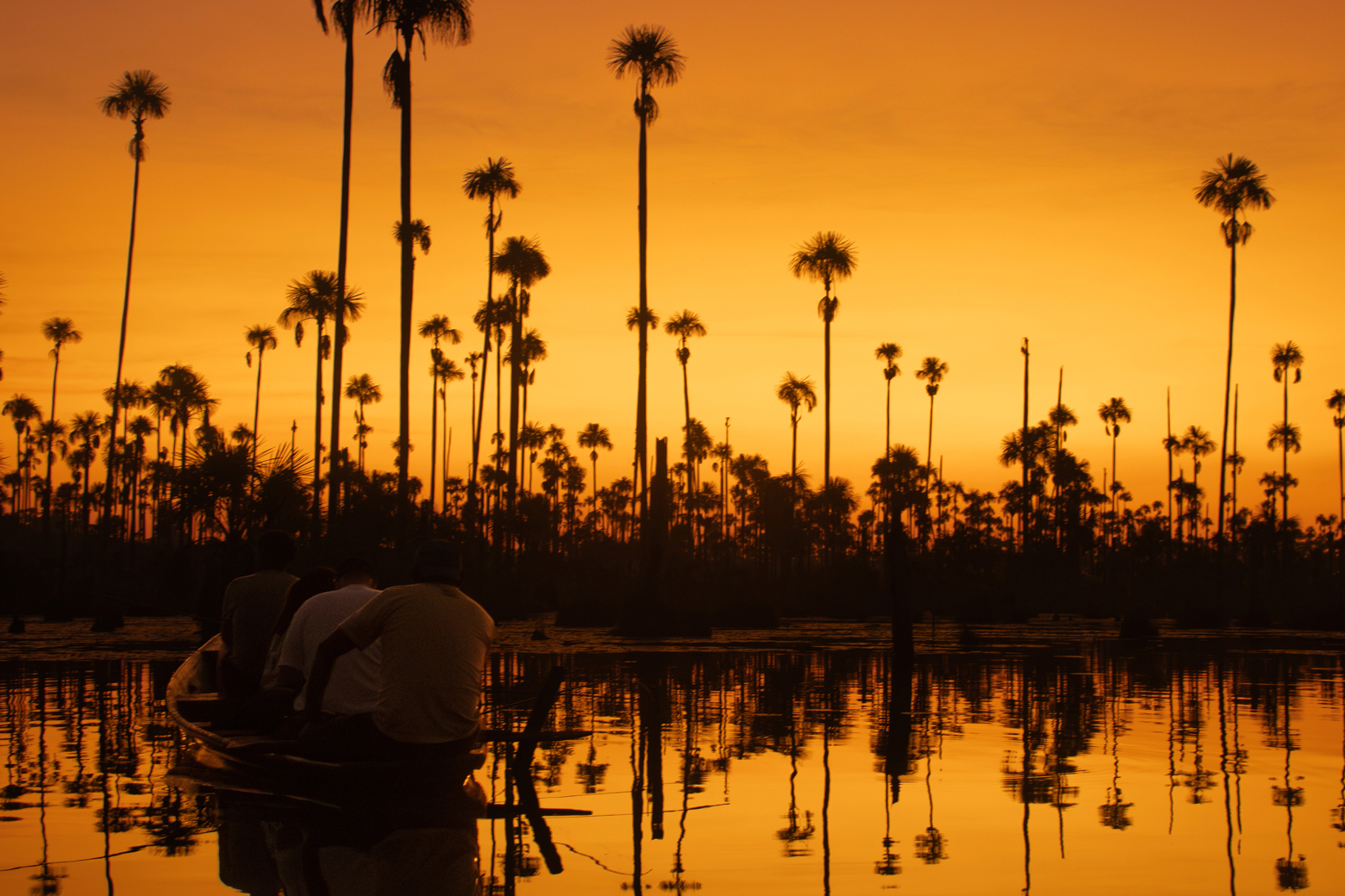 Shadows of people on a small rowboat as the sun sets