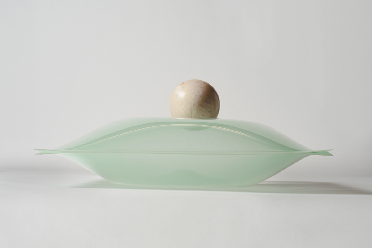Image of a sculpture, a large pearl on top of a pillow made of glass