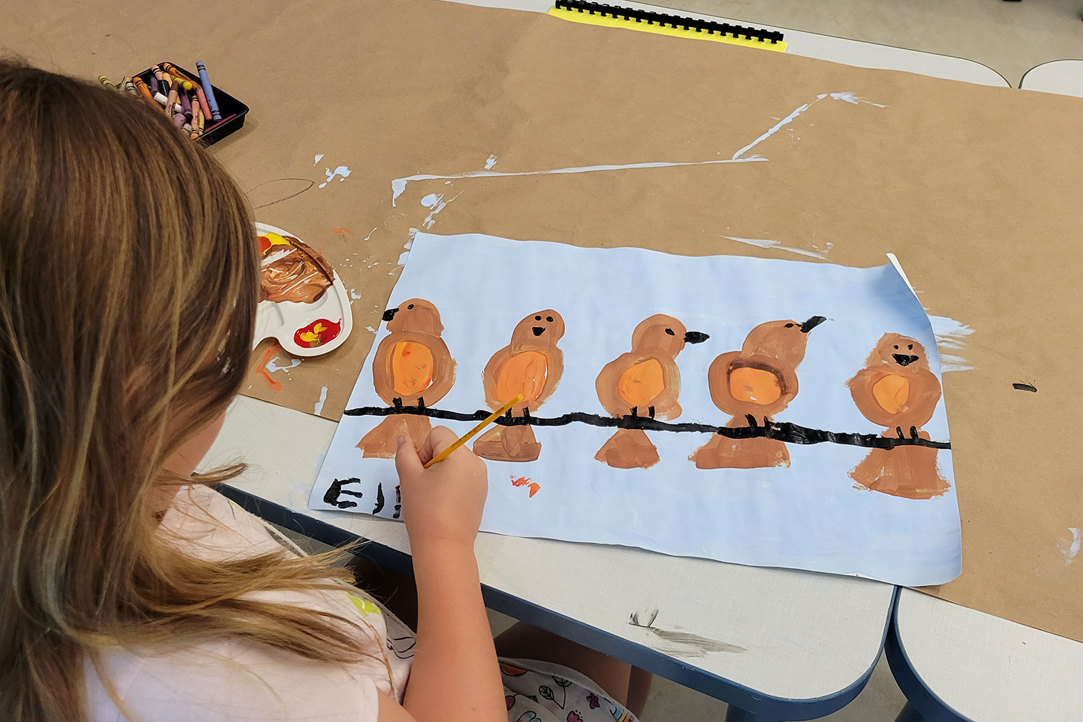 Young girl painting a picture of birds on a branch