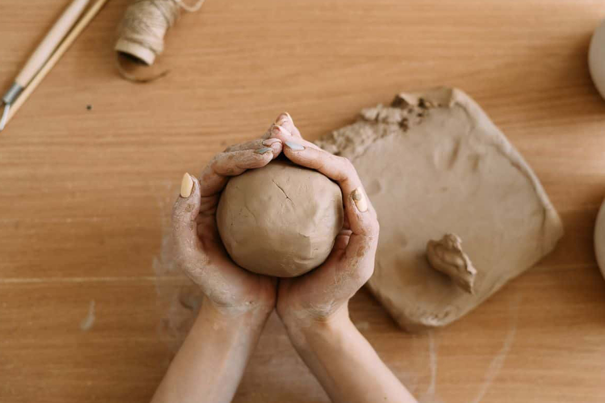 Cupped hands hold a ball of clay