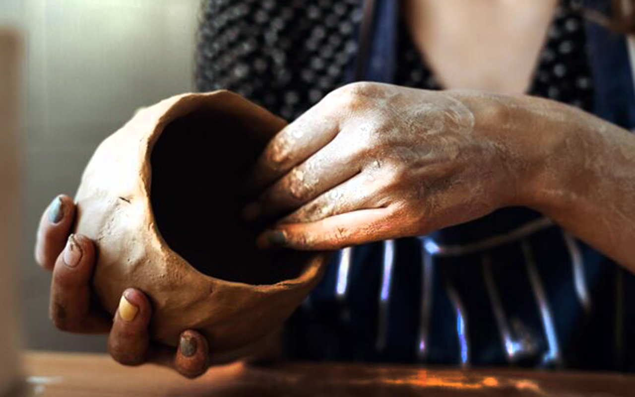 Closeup of hands forming clay on a pottery wheel