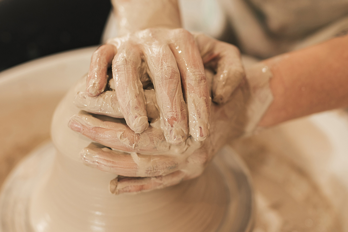 Closeup of hands forming clay on a pottery wheel