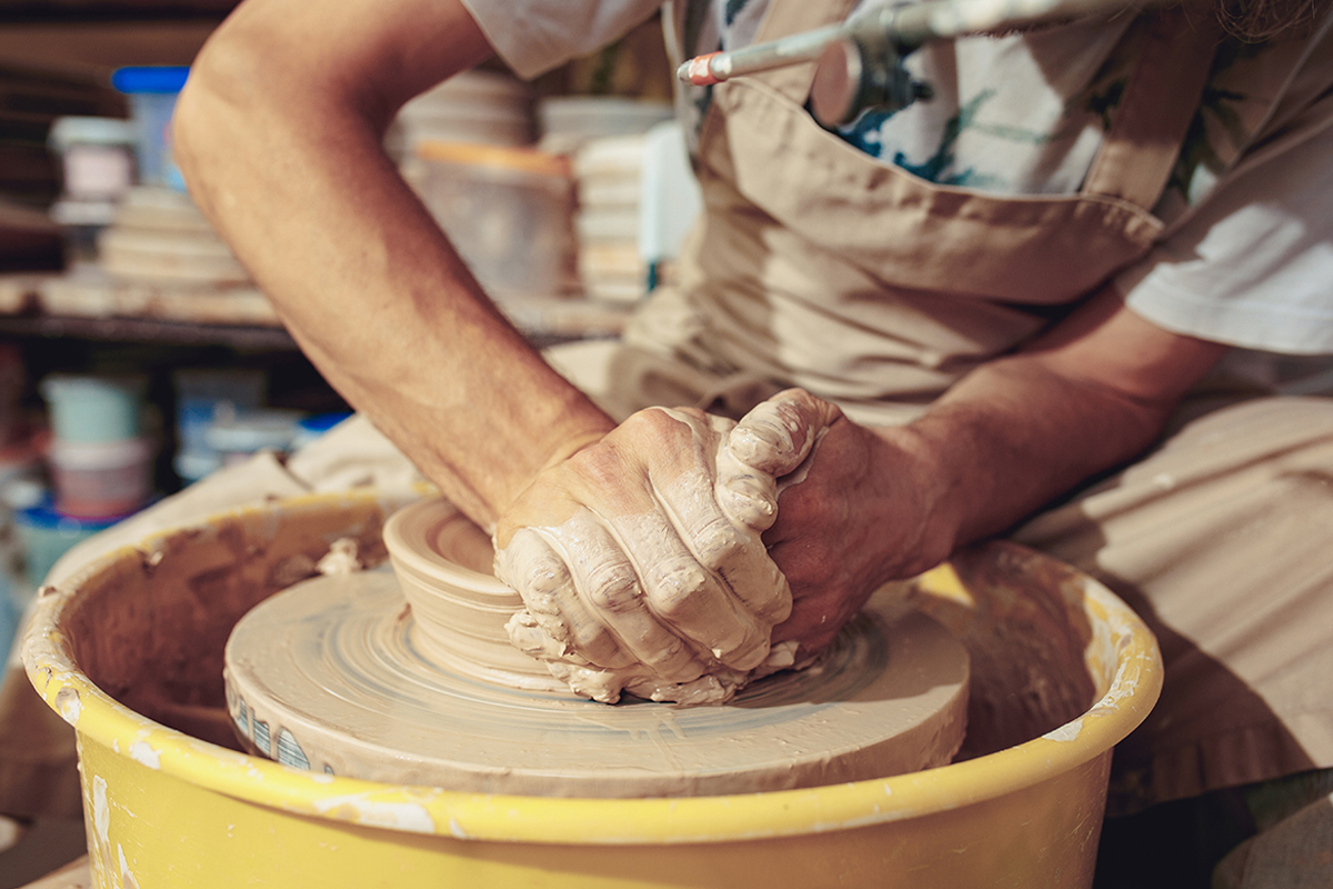 Potter pushes clay on a wheel
